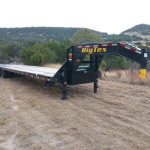 A Big Tex flatbed trailer parked on rough terrain.